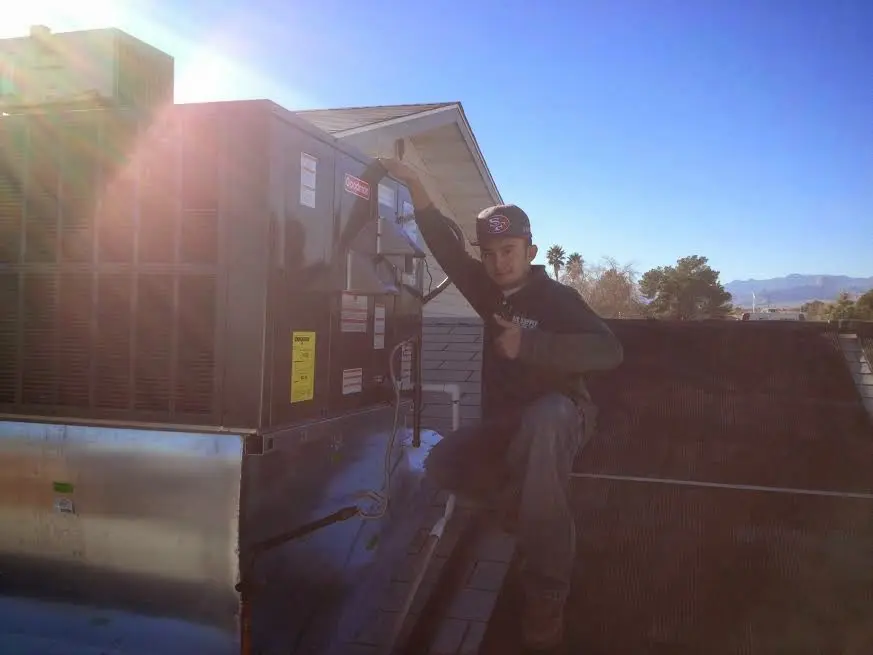 HVAC technician performing AC Tune-Up on a rooftop unit in Scott